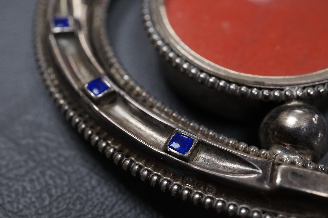 A late Victorian novelty silver and enamelled small photograph frame, modelled as a horseshoe, Birmingham, 1895, height 69mm together with a late 19th century Hanau white metal fish pin cushion(lacking cushion).